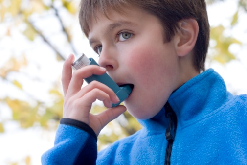 Boy (10-11) using inhaler